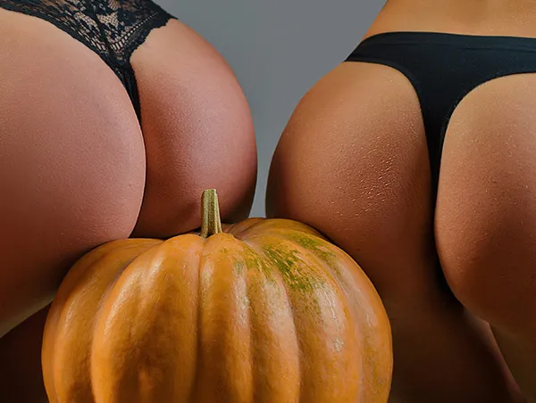 Two sexy ladies' arses sitting on a pumpkin